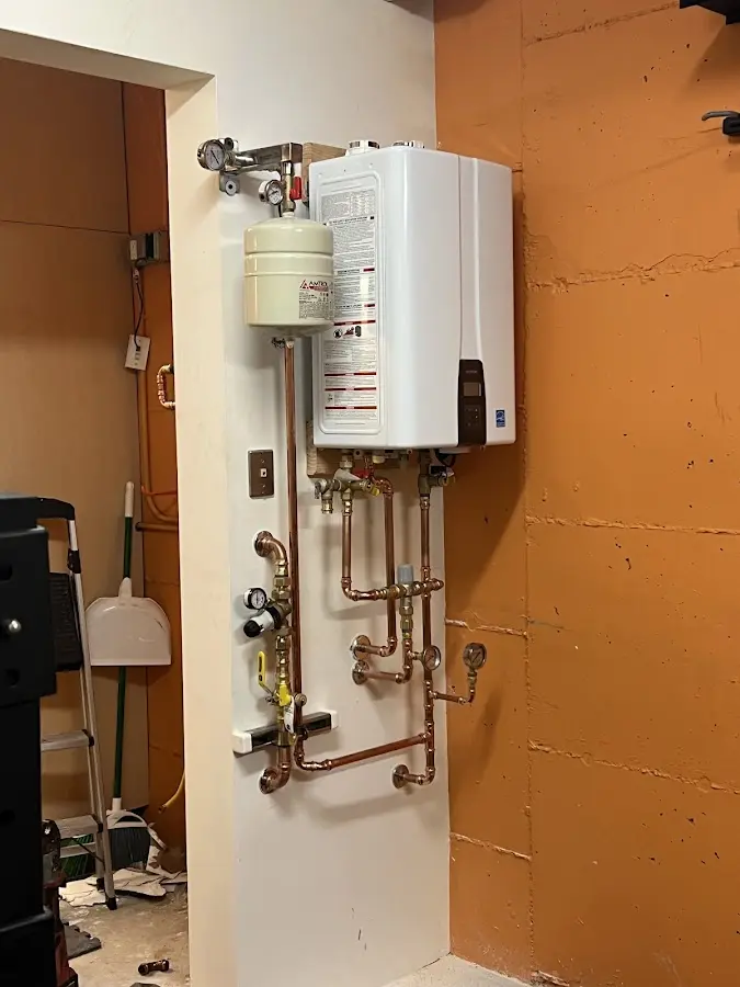 Plumbing technician inspecting water heater connections in Posen